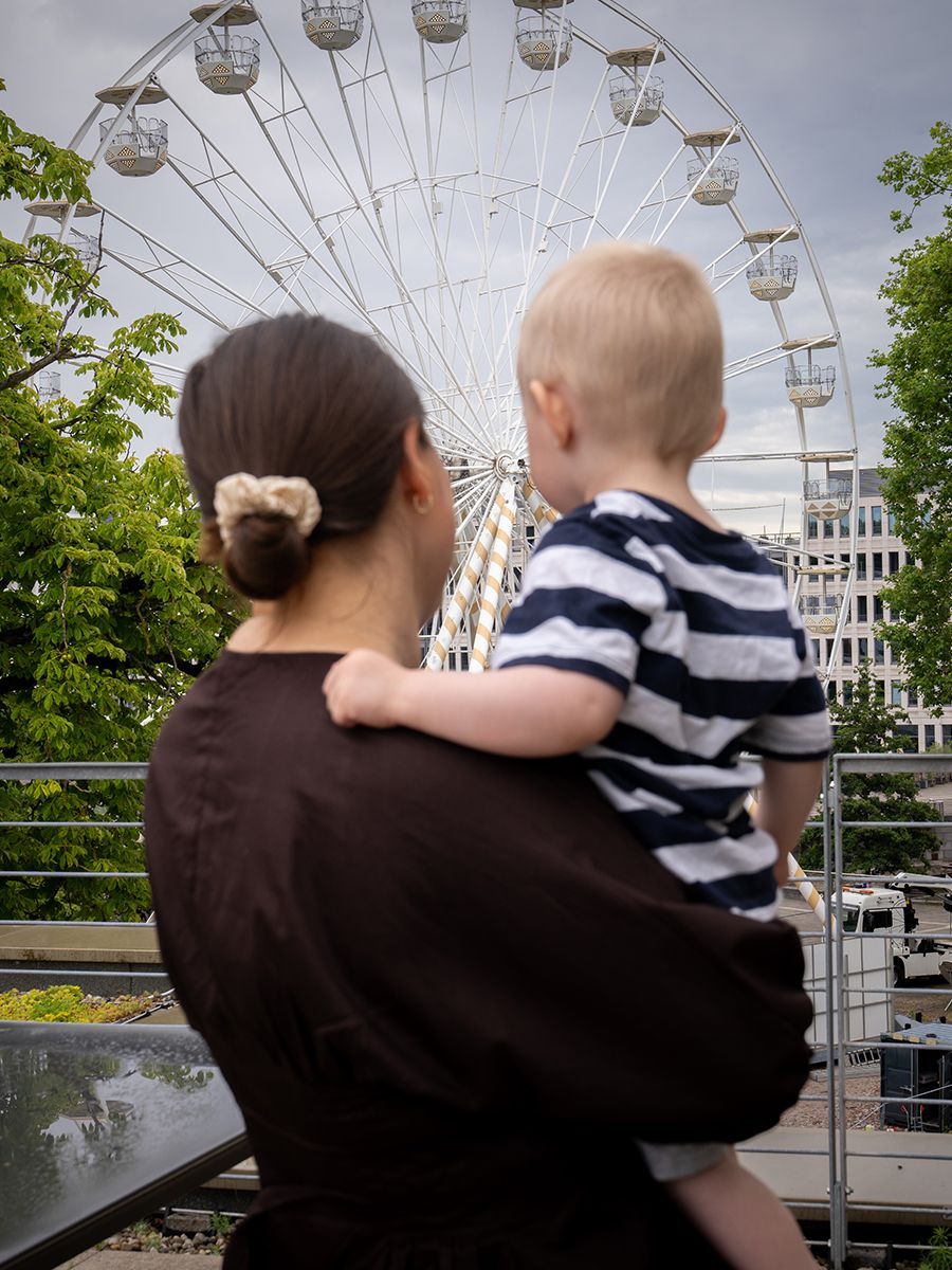 Mitarbeiterin mit Kind beim Blick auf ein Riesenrad