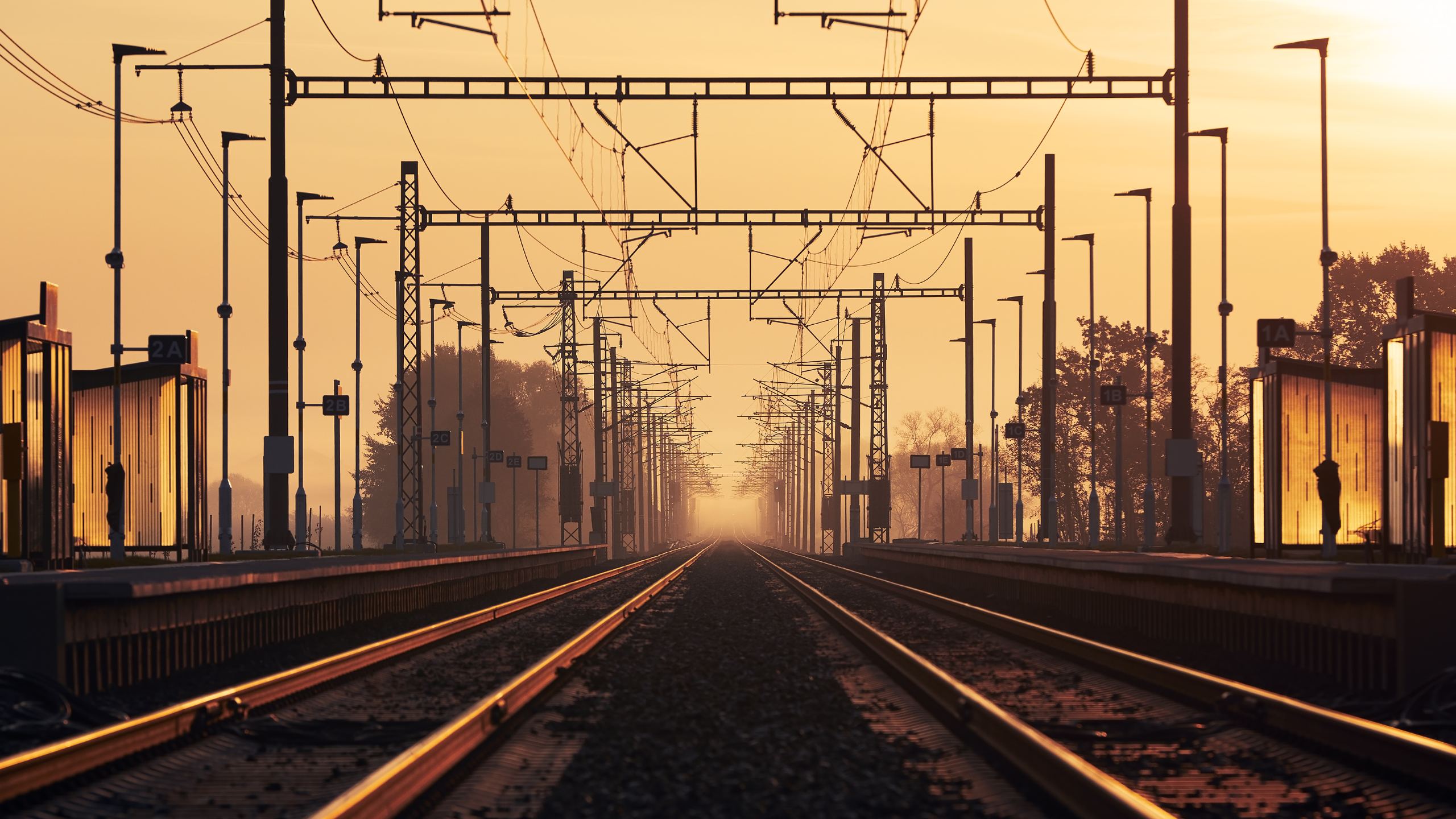 Bahnstrecke mit Oberleitung im Licht des Sonnenaufgangs